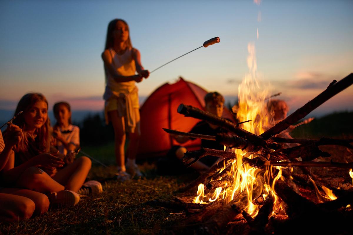 Children roasting marshmallows around a campfire at sunset